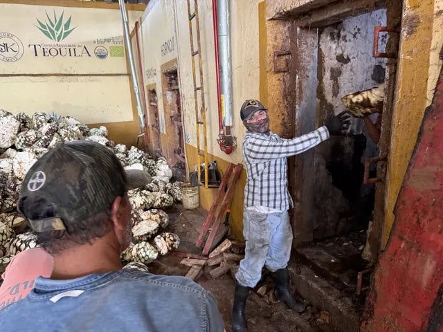 Workers at a horno door beside piles of piñas